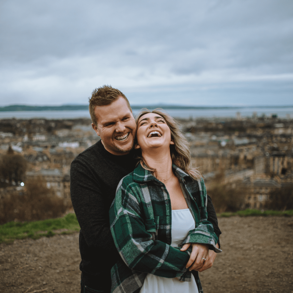 happy couple laughs while having photos taken at calton hill with docuemtnary wedding photographer in edinburgh scotland