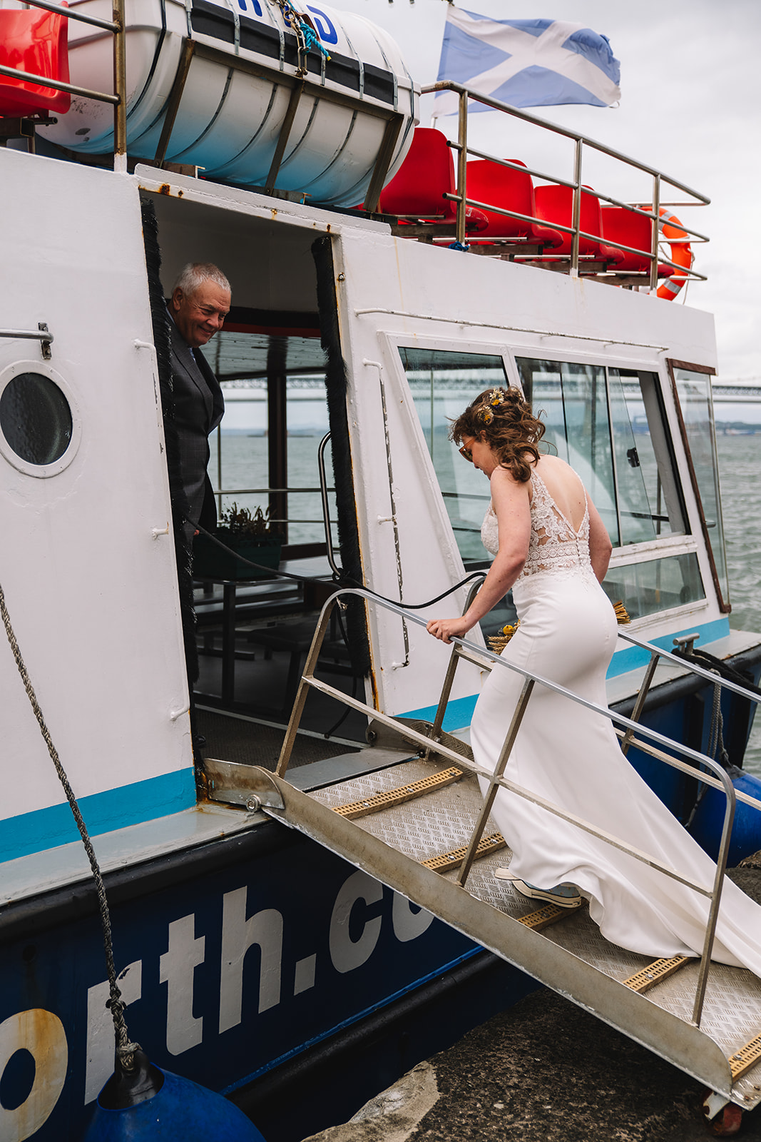 Bride stepping onto boat in wedding dress during elopement.