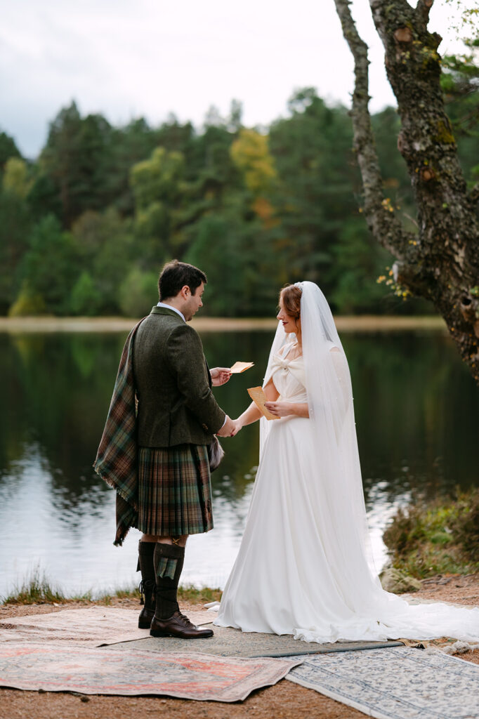 Bride and groom exchanging vows by lakeside in Scotland.