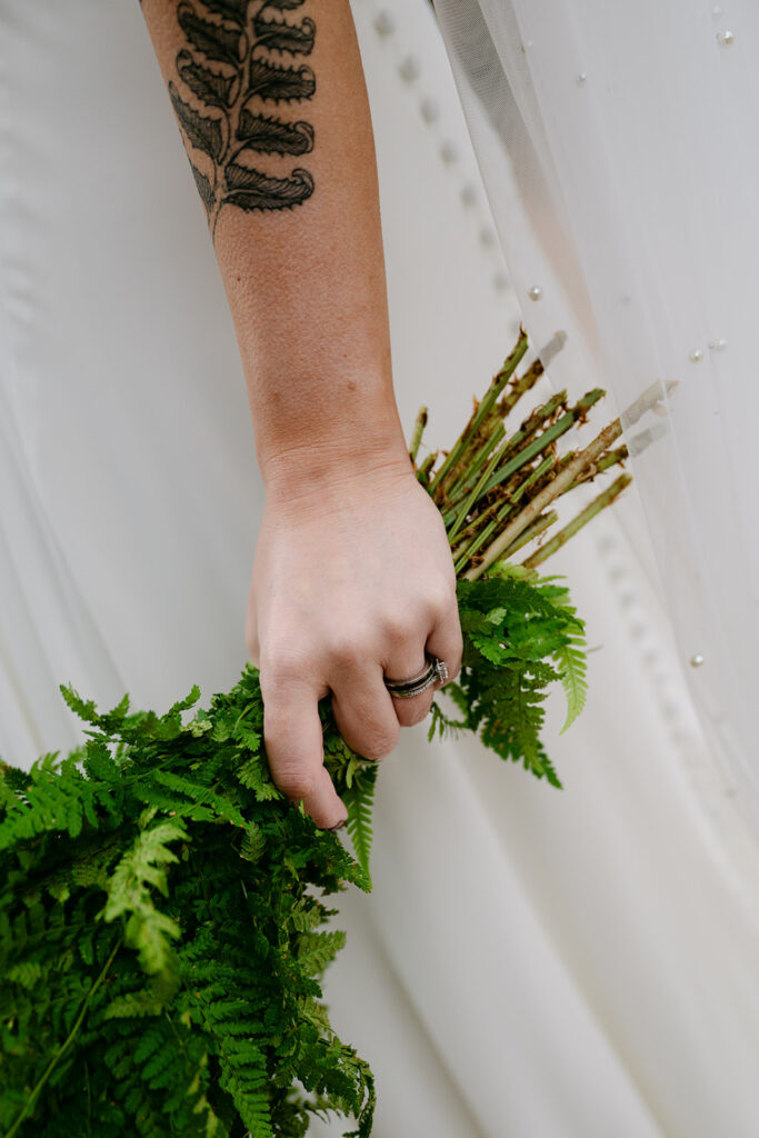 Bride holding greenery bouquet close-up detail shot.