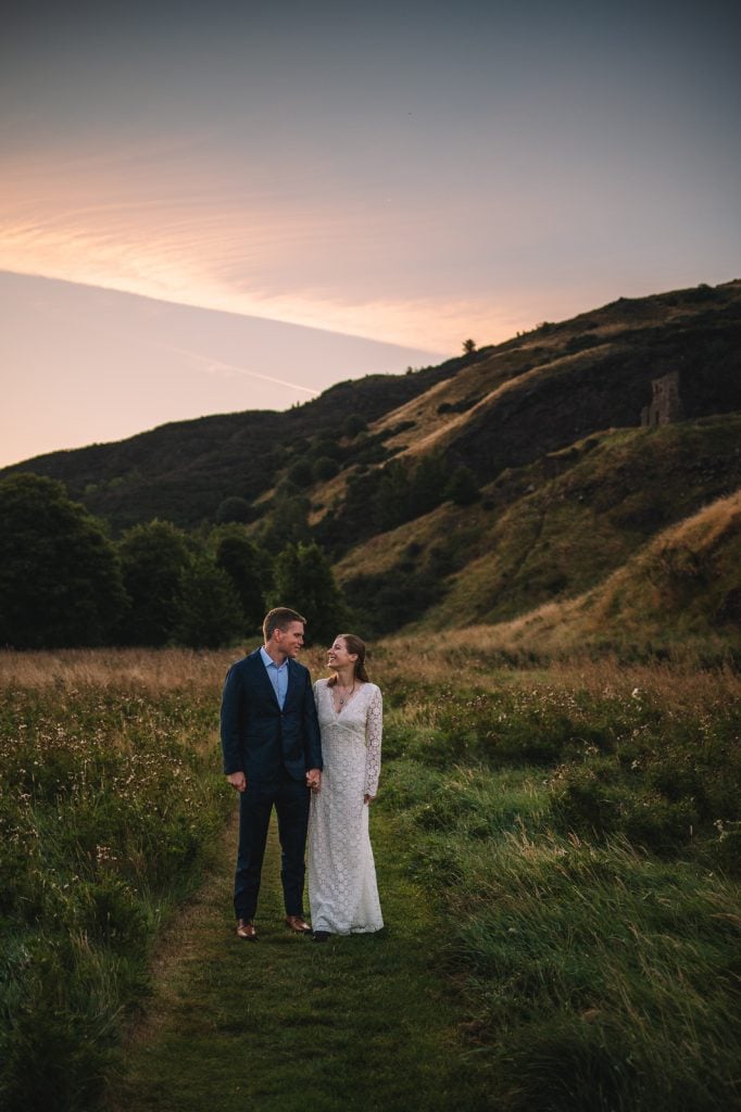 Couple standing together in open valley with hills behind