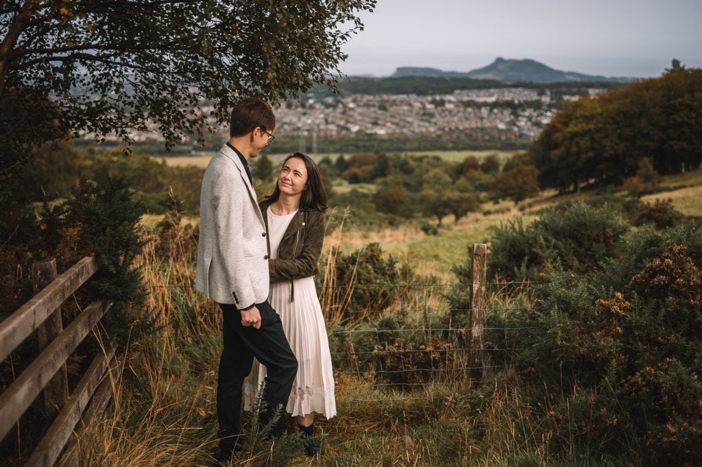 Couple standing together in hillside landscape overlooking city
