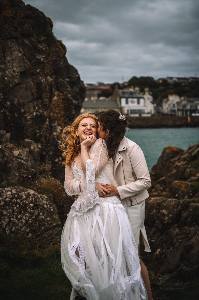Couple embracing among coastal rocks near seaside village