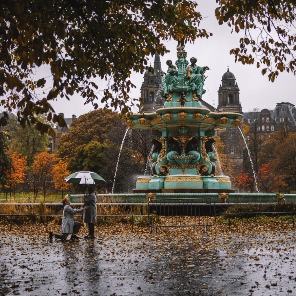 couple proposal by Ross Fountain in Princes Street Gardens during autumn rain