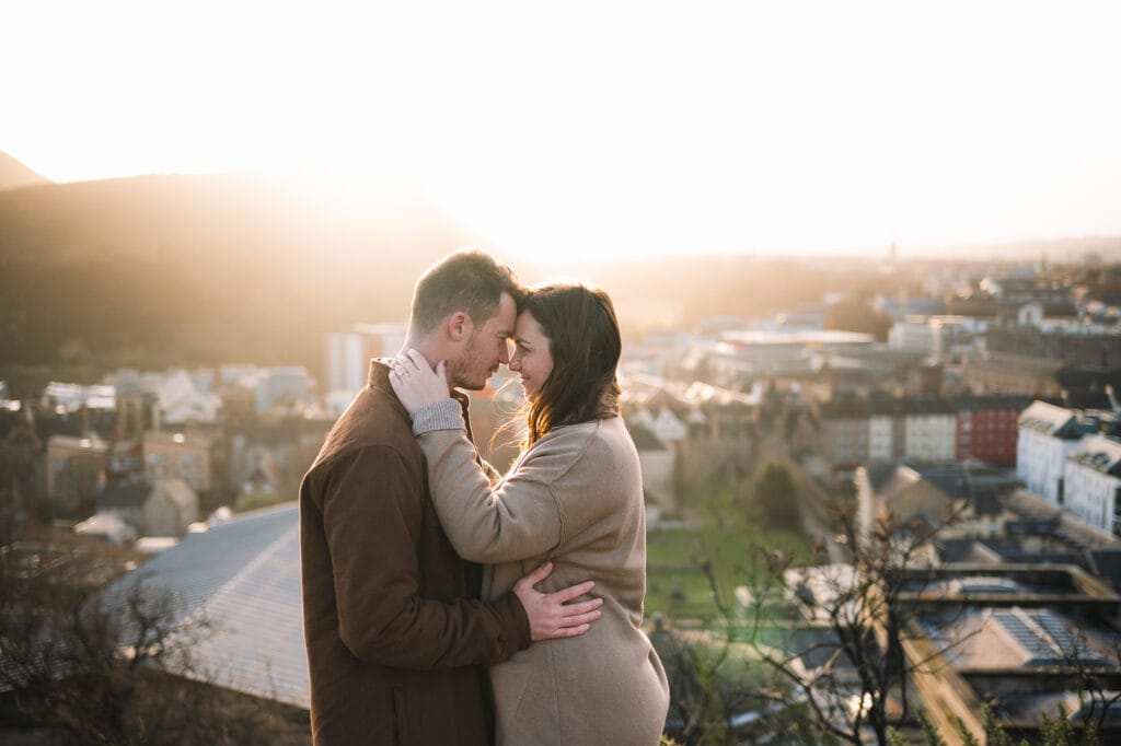 Couple kissing in golden sunset light overlooking city