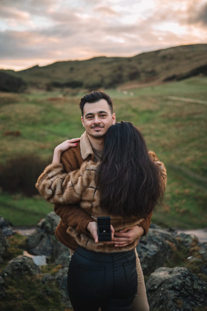 Couple embracing in grassy hillside landscape