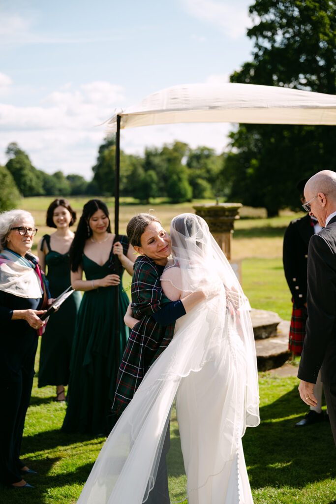 Bride greeting guests during outdoor wedding ceremony in garden setting.