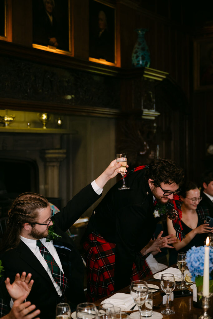 Guest raising glass for toast during lively wedding reception.