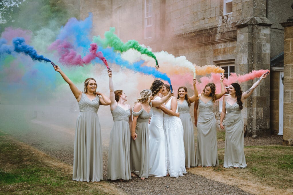 Bridal party celebrating with colorful smoke bombs