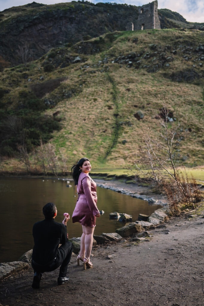 Man porposing by loch with hills in background