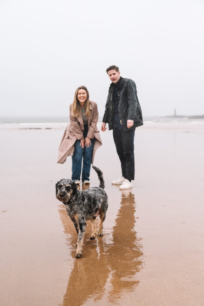 Couple embracing on rocky beach with dog