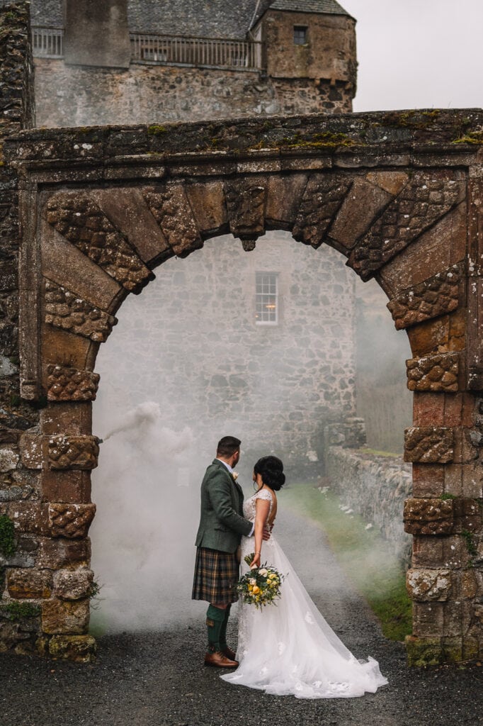 bride and groom framed by stone archway in courtyard