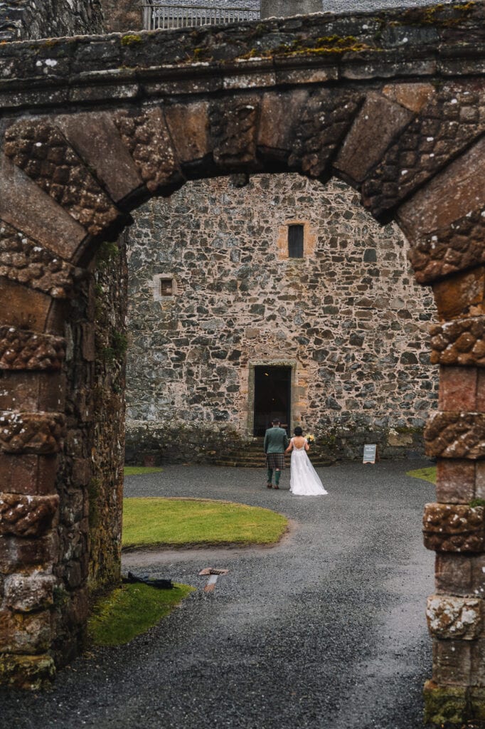 bride and groom framed by stone archway in courtyard