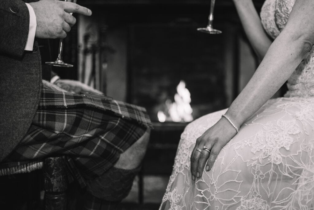 black and white detail of couple holding hands by firelight