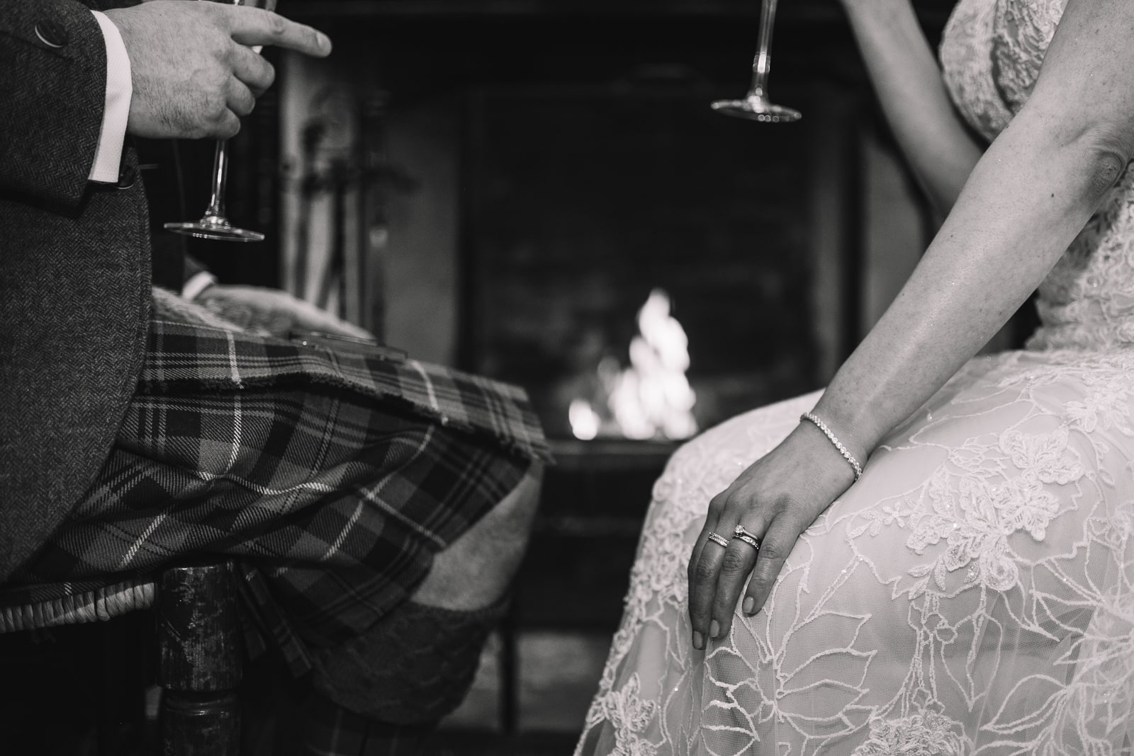 black and white detail of couple holding hands by firelight