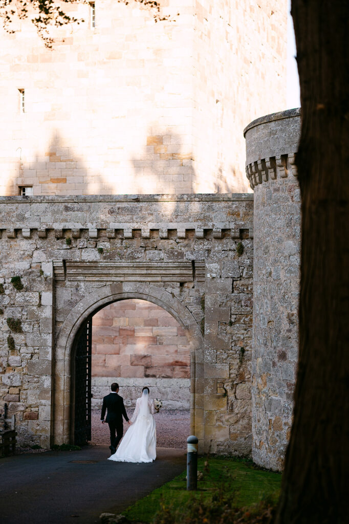 Stone archway entrance with couple walking through historic setting.