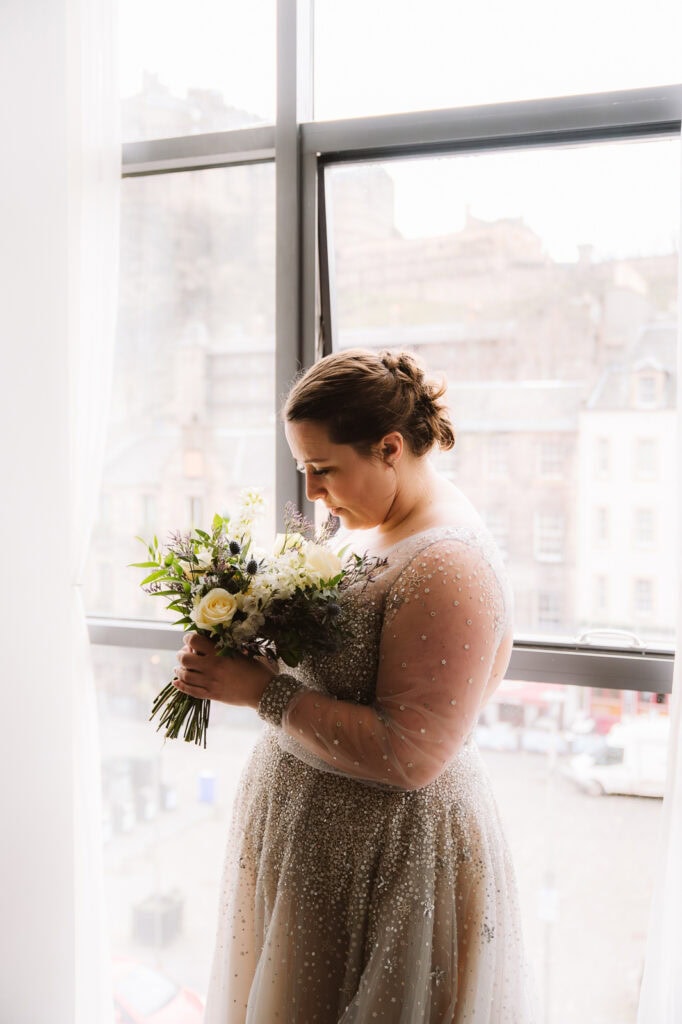 Bride holding bouquet by window in natural light
