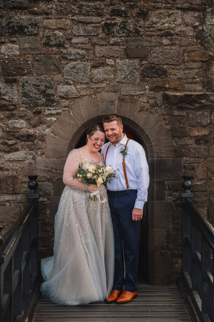 Couple standing together in stone archway at Edinburgh Castle