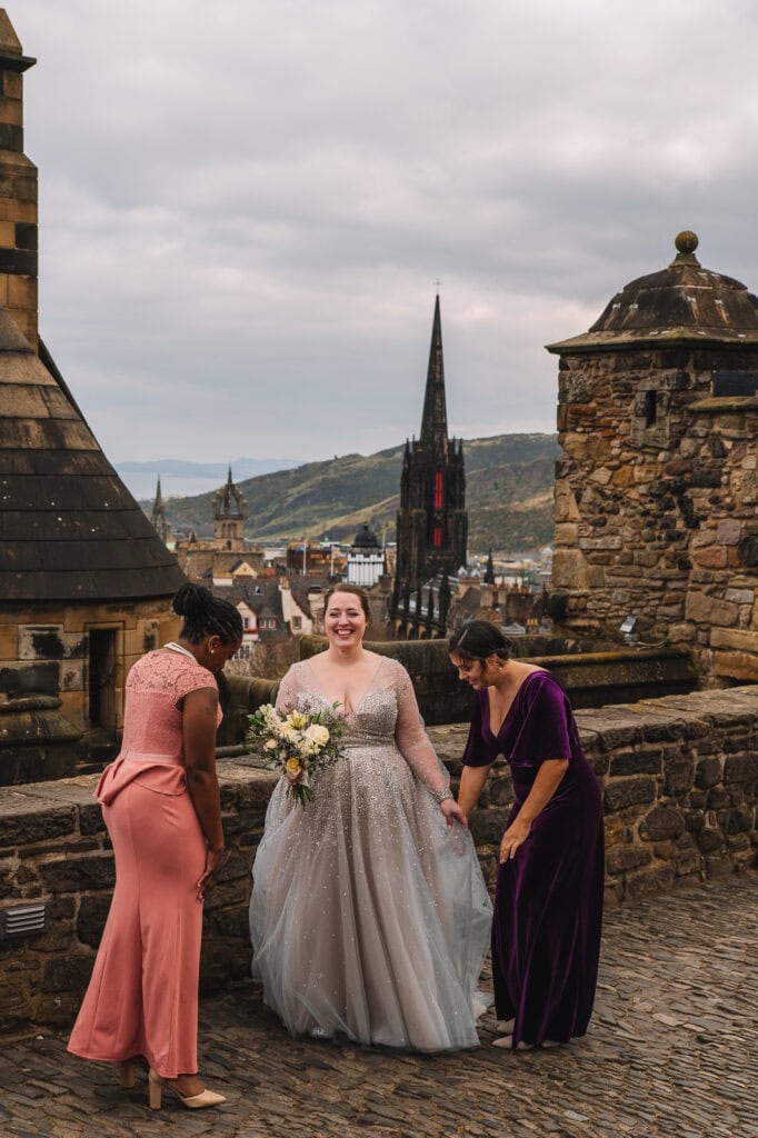 Bridesmaids helping bride with bouquet on castle terrace