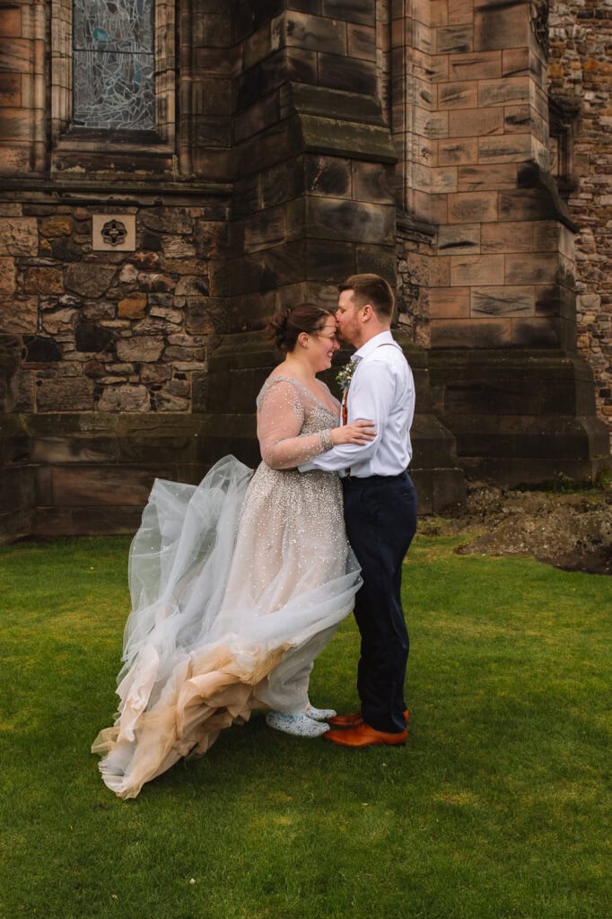 Couple embracing beside stone walls of Edinburgh Castle