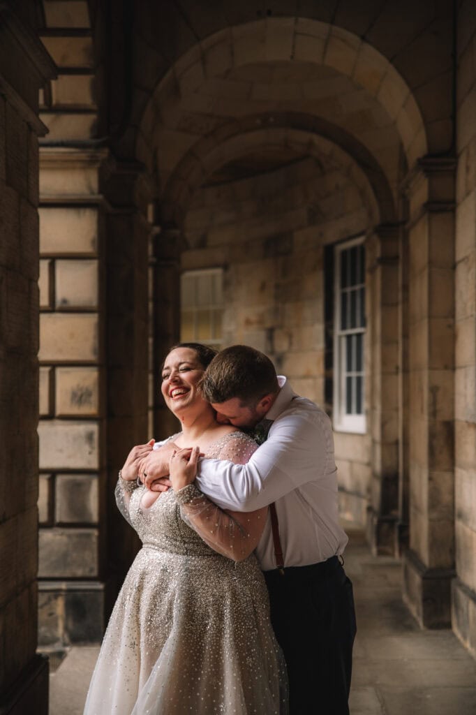 couple embracing under stone arches in Edinburgh