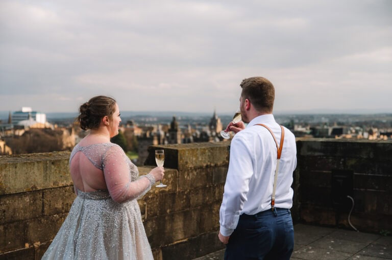 Couple standing at Edinburgh Castle viewpoint overlooking the city