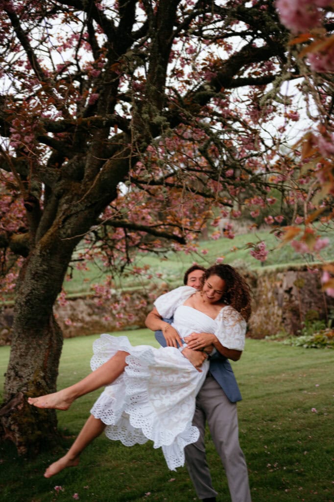 Couple embracing beneath a flowering tree in a garden