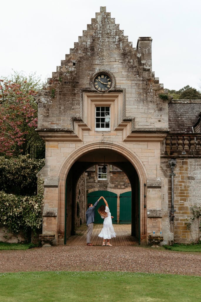  Bride standing beneath an arched stone entrance at a wedding venue