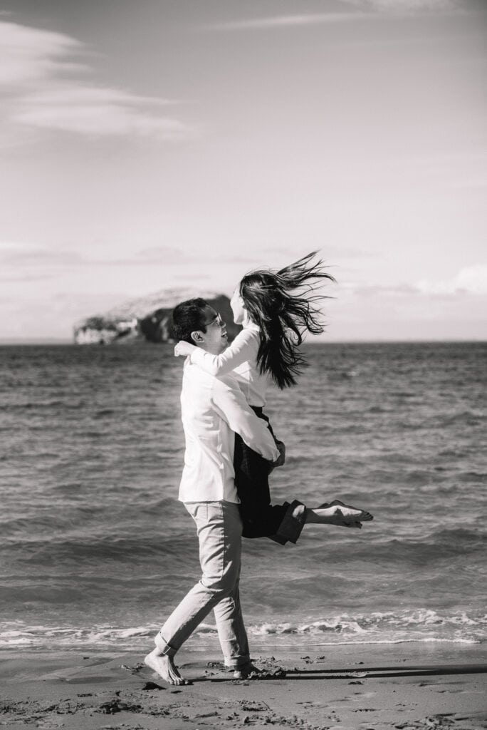 Black and white image of couple playing together on the beach