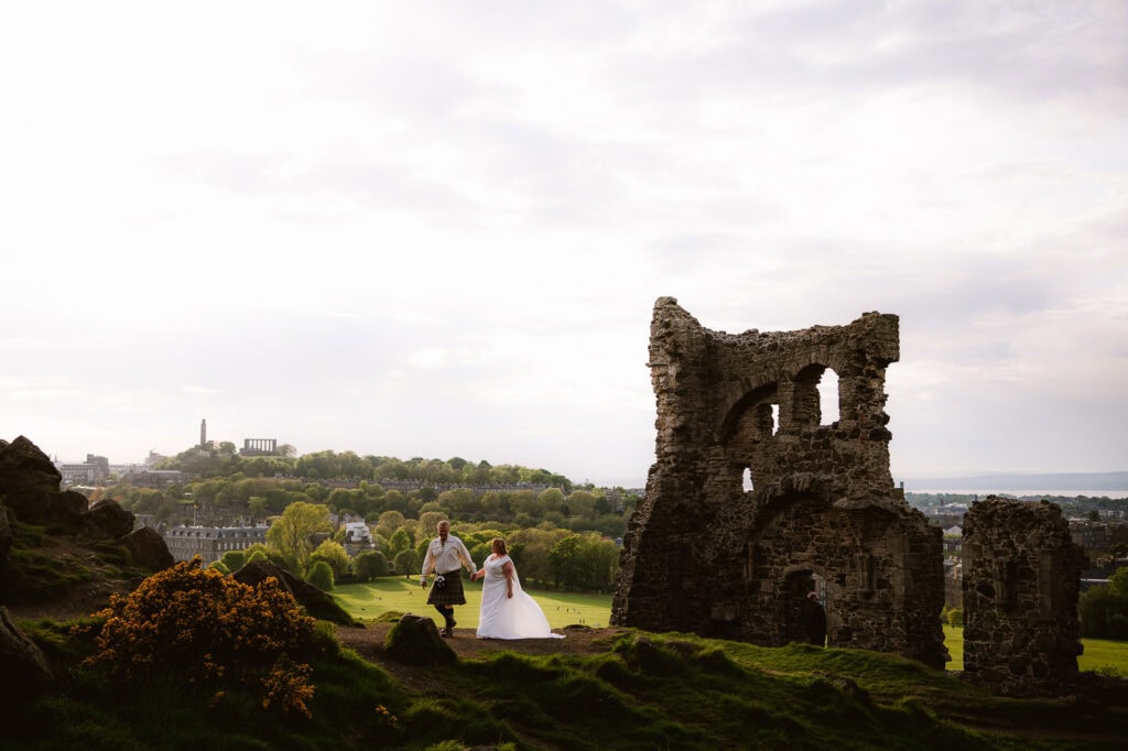 Bride and groom standing near coastal ruins overlooking the sea