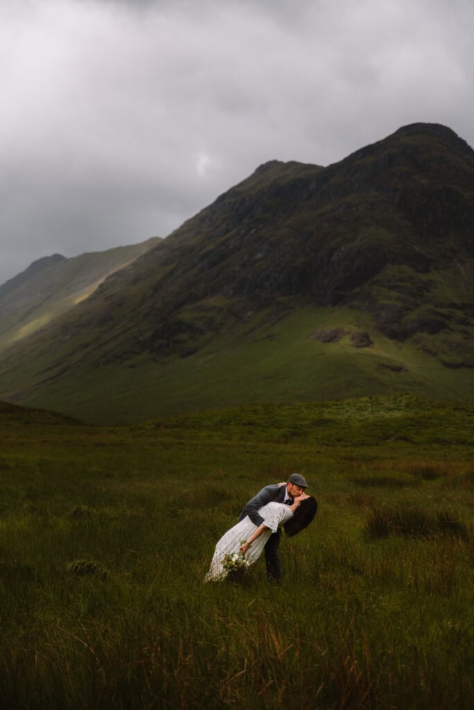 Bride playfully bending in grassy Highland landscape during photos