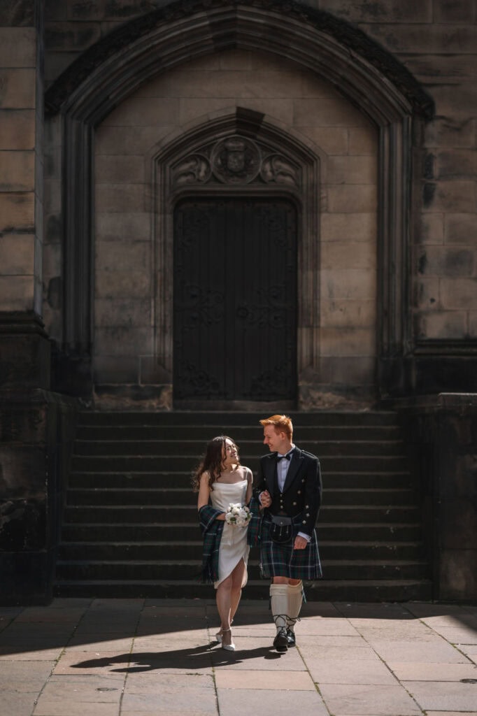 Couple standing near historic ruins with soft evening light in Scotland