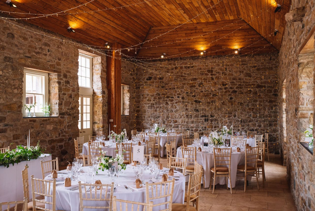 Reception setup inside rustic barn with decorated tables