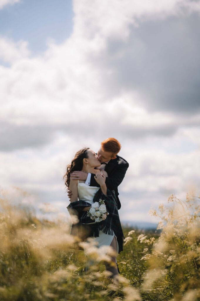 Couple embracing in tall grass during sunset in Scotland