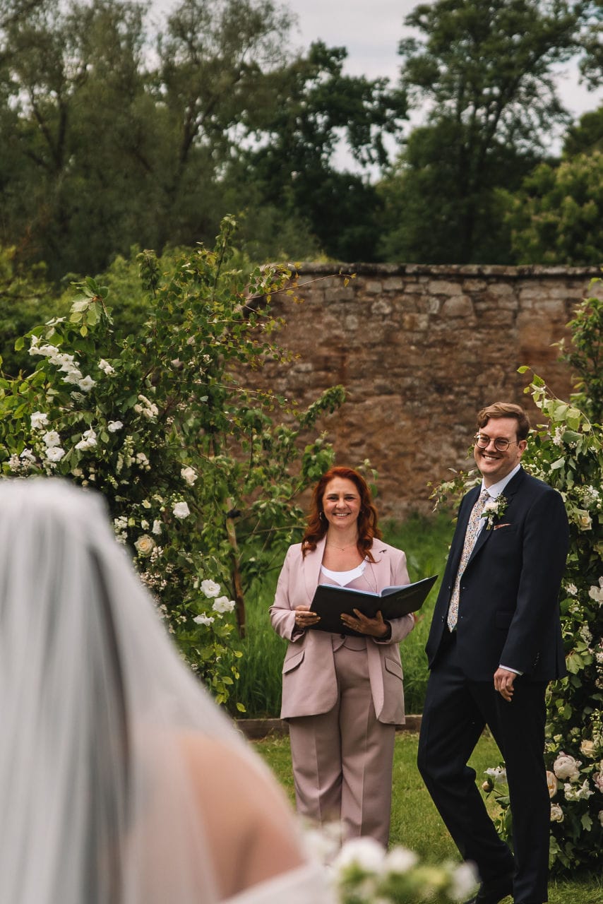 Officiant smiling during ceremony in garden setting