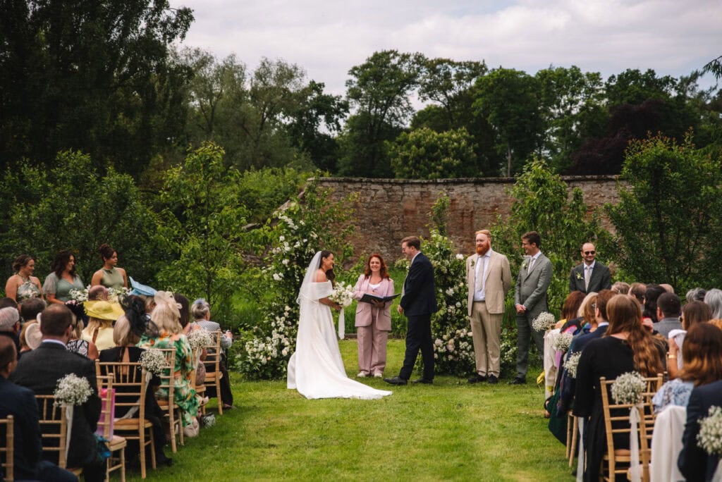 Wide shot of outdoor ceremony with guests seated on lawn