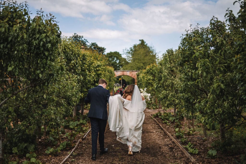 Bride and groom walking away together along a garden path