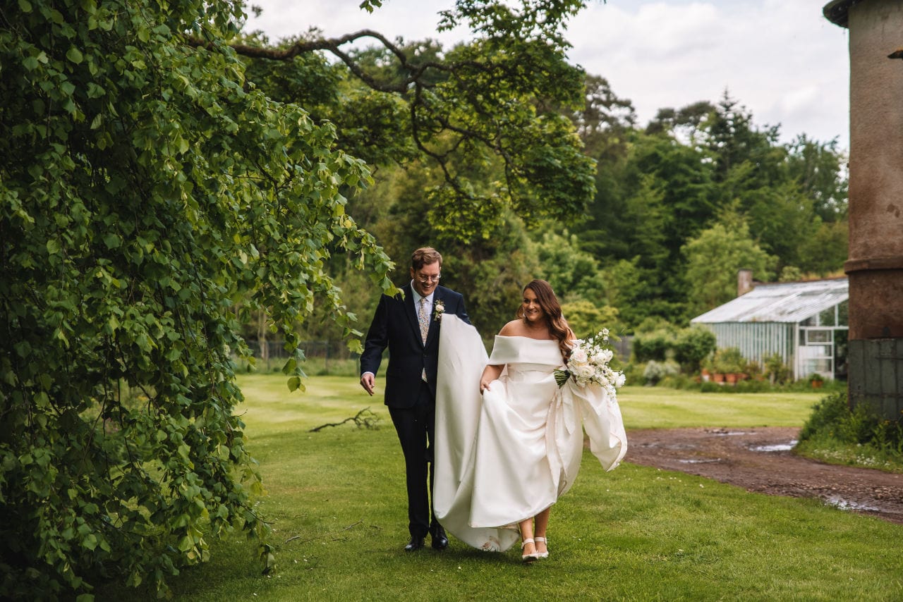 Couple walking across lawn holding hands after ceremony