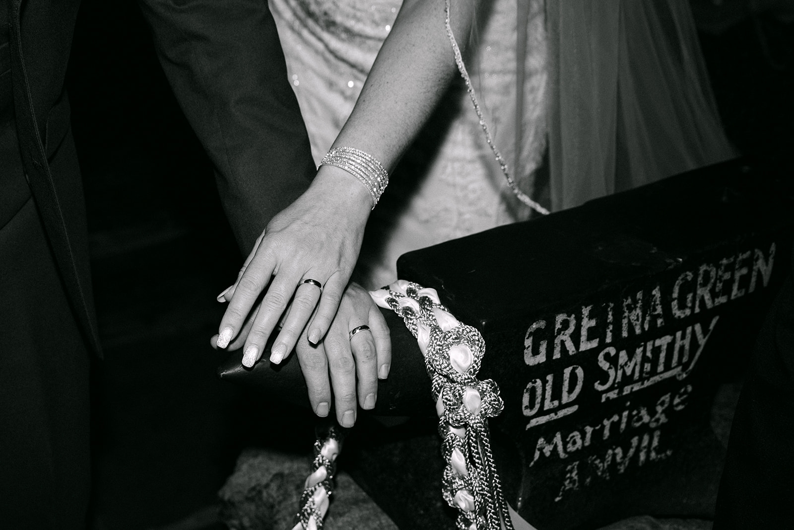 bride and groom's hands sit on top of gretna green old smithy anvil
