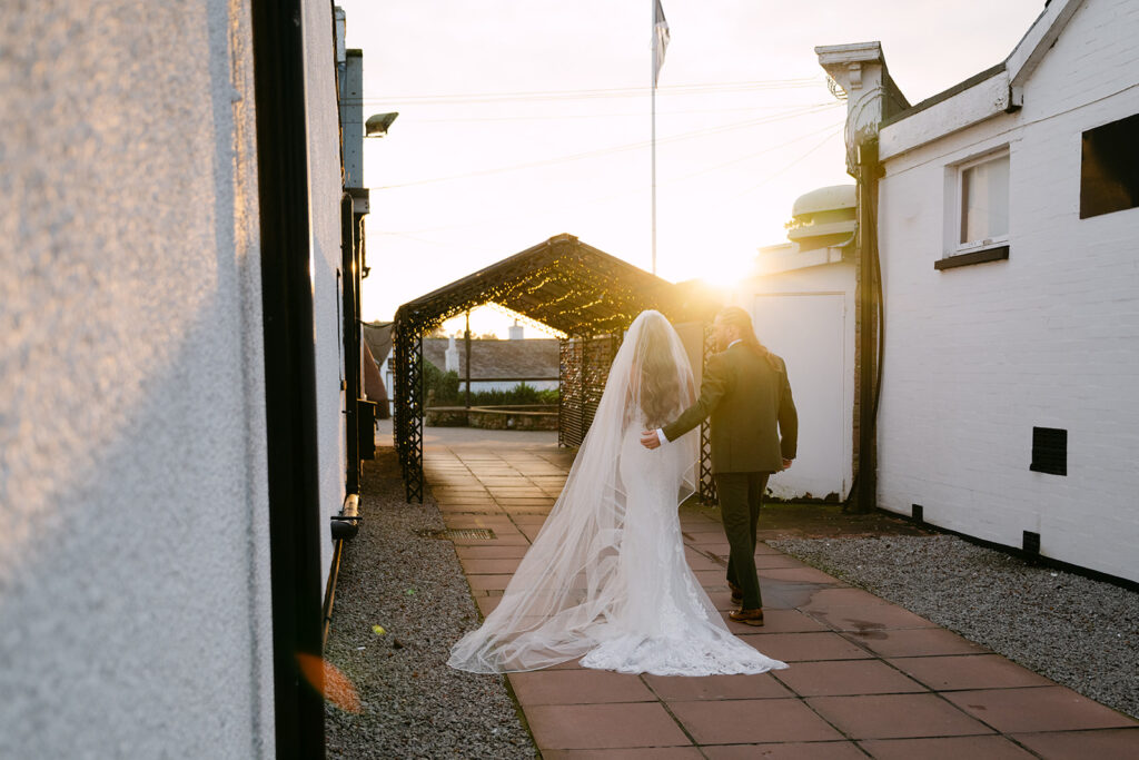 bride and groom walk towards sunset at gretna green