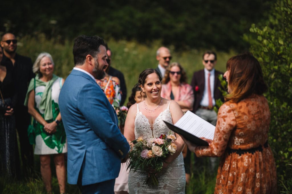 Bride and groom holding hands during intimate outdoor ceremony
