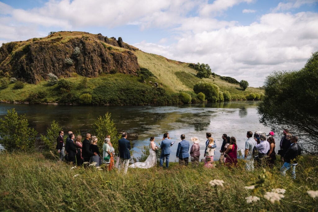 Guests gathered for ceremony beside riverside landscape