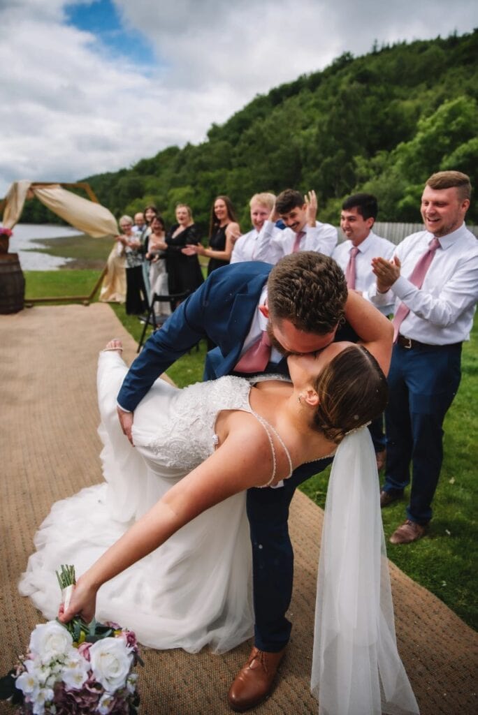Groom dipping bride during celebration outdoors