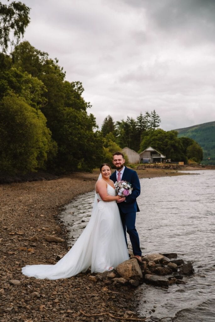 Couple embracing beside river in woodland