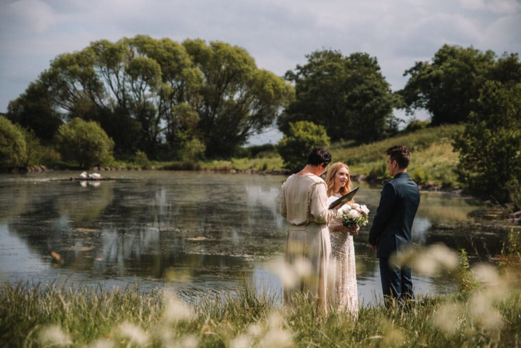  Wedding ceremony beside river with guests gathered