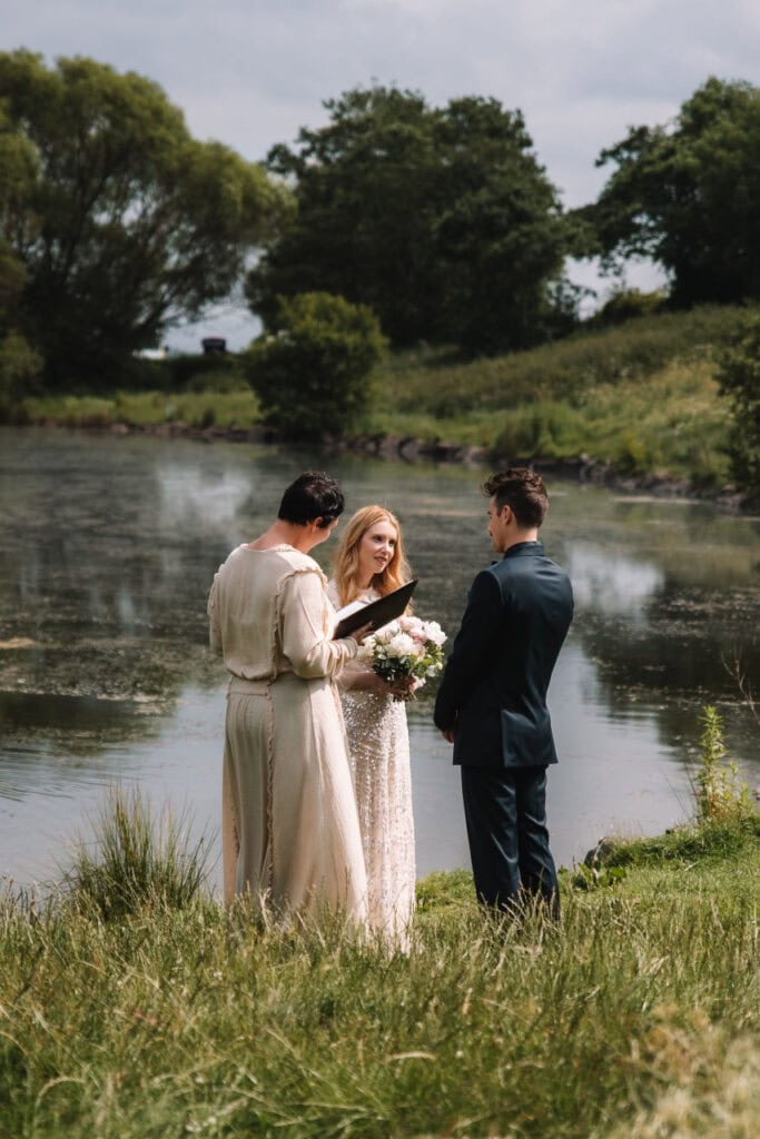 Couple exchanging vows beside calm water