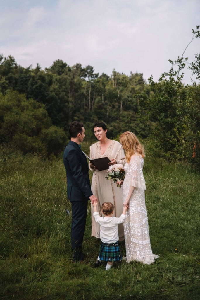 Couple with child during outdoor ceremony by river