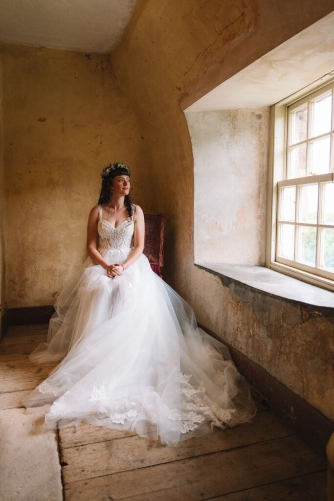 bride sits on a chair by a window at Neidpath Castle