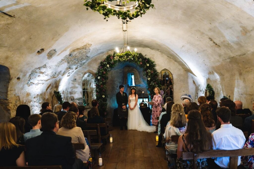 bride and groom stand at the top of the aisle in scotland castle wedding