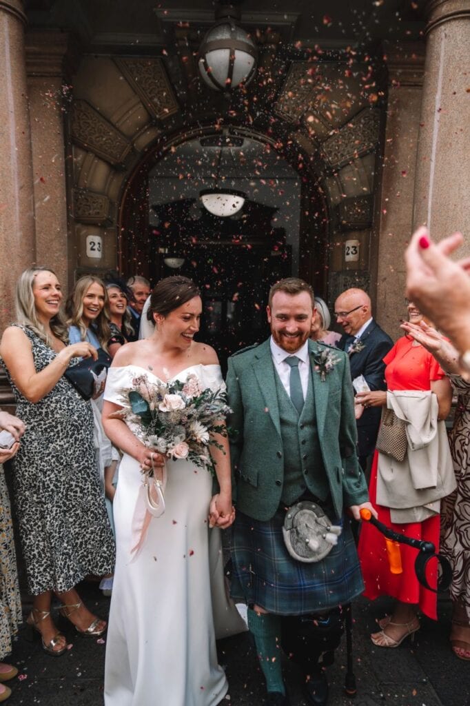 Bride and groom exiting ceremony surrounded by cheering guests